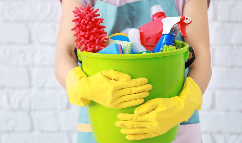 Woman in yellow gloves holding green basket