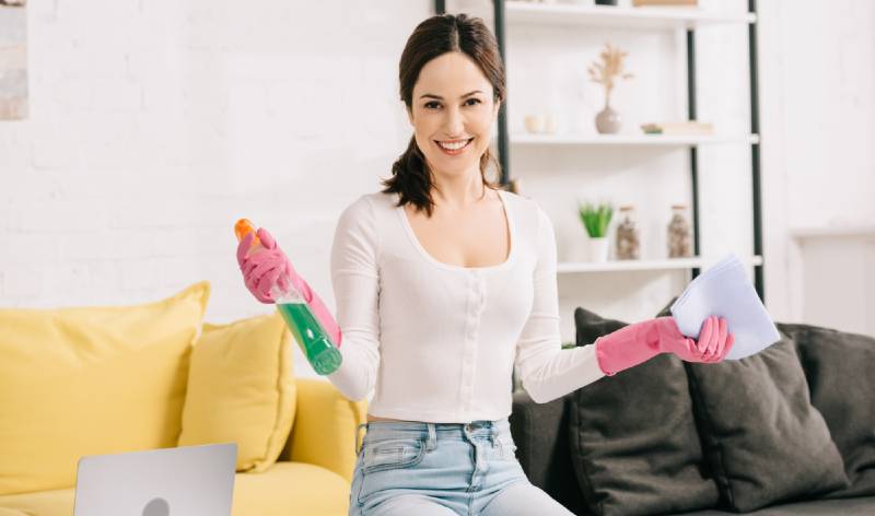Women in white t-shirt and pink glops holding spray bottle and cloth