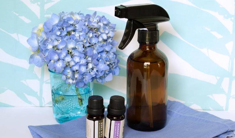 One spray bottle and two small bottle on towel with flower glass