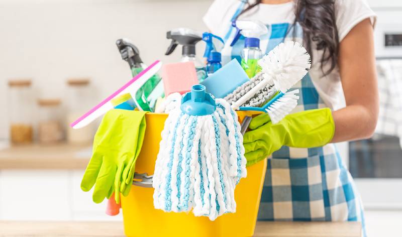 Woman holding a yellow basket in hand with tools and supplies