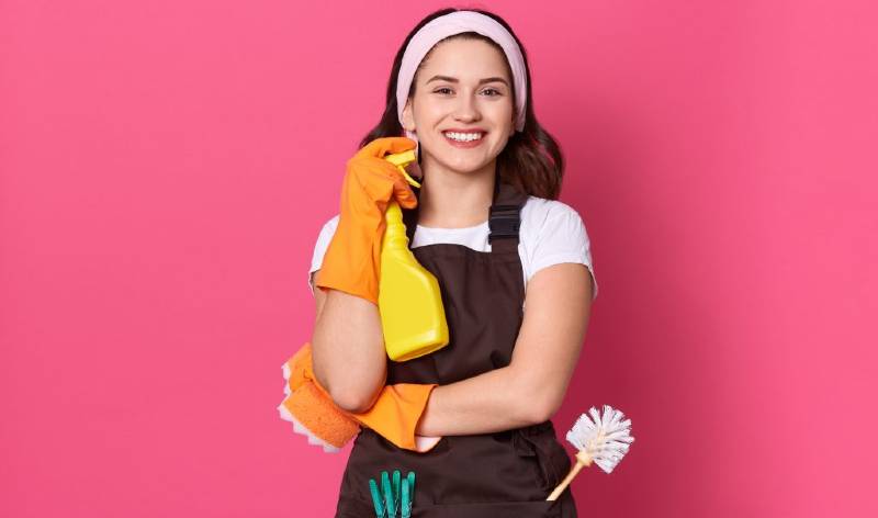 Woman in orange gloves holding yellow bottle in hand