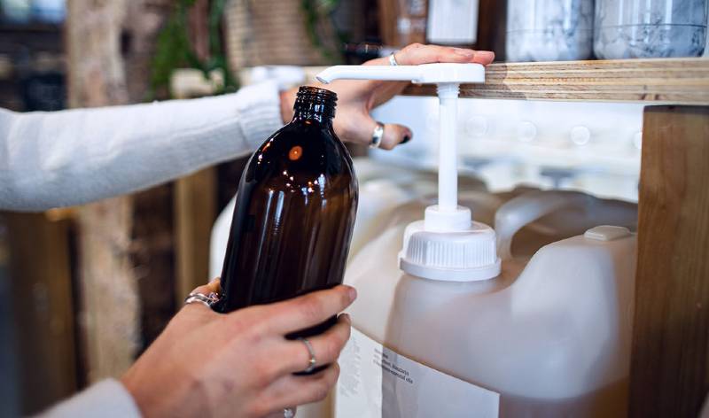 Hands of a woman in white dress holding a bottle in one hand.