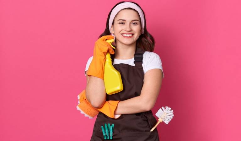 Woman in orange gloves holding a yellow bottle and smiling