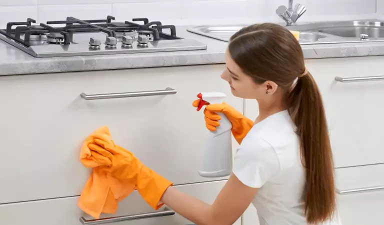 woman cleaning a kitchen cabinet