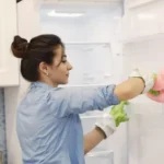 young woman cleaning a fridge