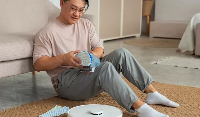YOUNG MAN WITH A ROBOT VACUUM CLEANER