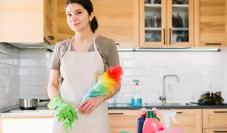 woman inside of her kitchen with some cleaning essentials