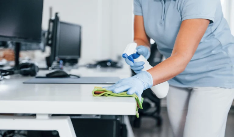 Close up view of woman in protective gloves that cleaning tables in the office