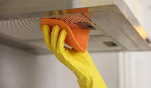 Man cleaning kitchen hood with rag indoors closeup