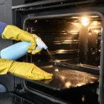 Close up of caucasian woman cleaning oven at home