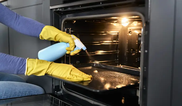 Close up of caucasian woman cleaning oven at home